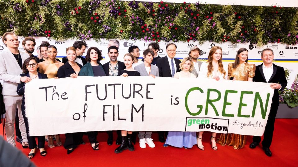 Filmschaffende stehen hinter einem weißen Banner mit der Aufschrift The Future of Film is Green.